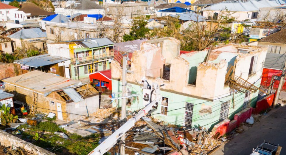 Jamaican resident repairing corrugated metal roof after Hurricane Melissa October 2025